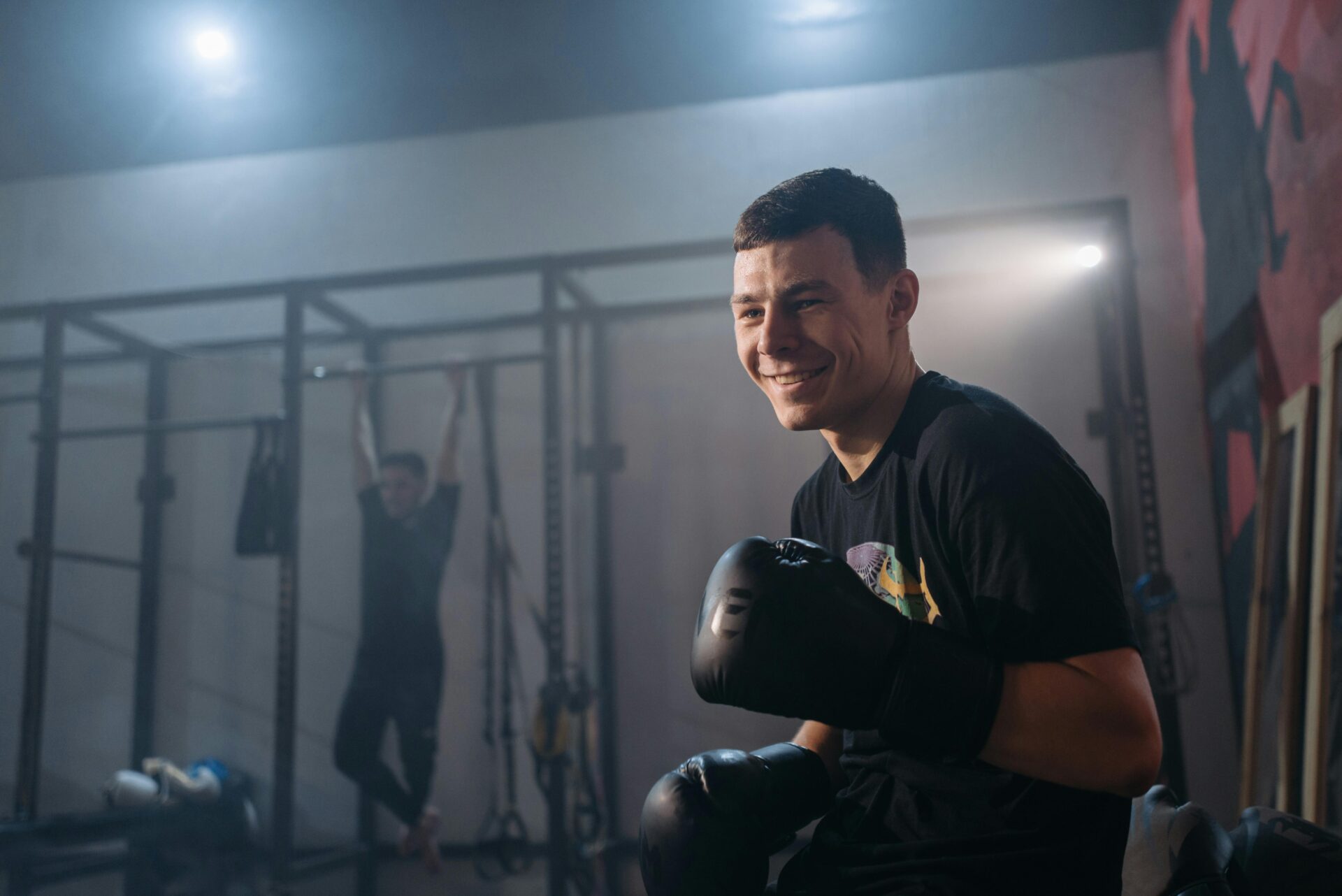Beim MMA-Training für Erwachsene lacht ein Sportler mit Boxhandschuhen.